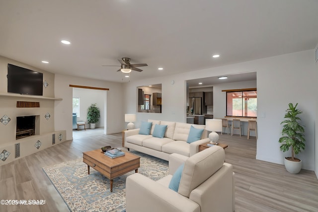 3053 W Lobo Rd, Tucson, AZ 85742 - living room featuring a fireplace with raised hearth, recessed lighting, light wood-type flooring, and ceiling fan