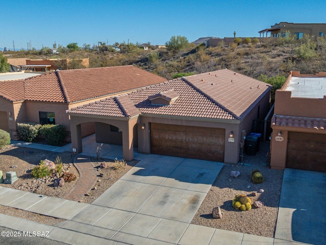 view of front of house with concrete driveway, a tiled roof, an attached garage, and stucco siding