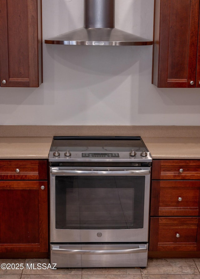 kitchen featuring light countertops, wall chimney exhaust hood, and stainless steel electric range