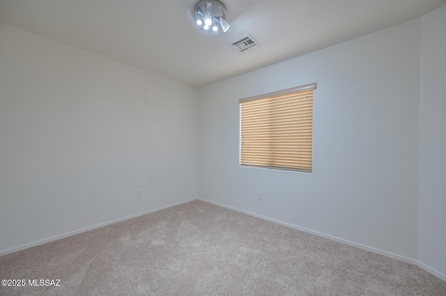 carpeted spare room with visible vents and baseboards