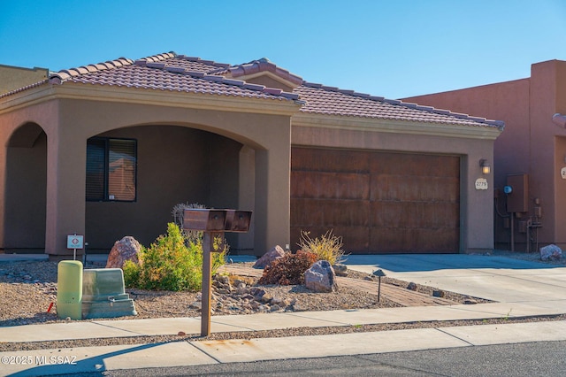 view of front of house with stucco siding, an attached garage, a tile roof, and driveway