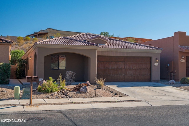 view of front of property with stucco siding, a tiled roof, concrete driveway, and a garage