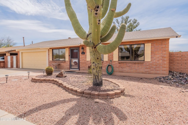 ranch-style house with an attached garage, driveway, fence, and brick siding