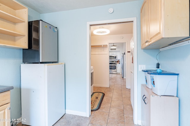 kitchen with appliances with stainless steel finishes, light tile patterned floors, and light brown cabinets