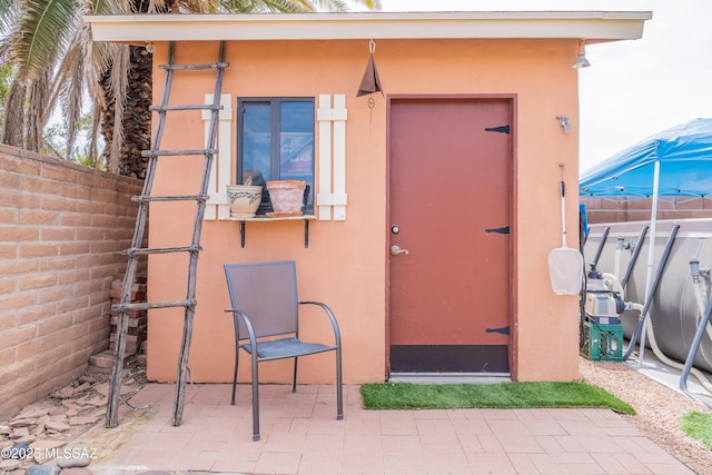 doorway to property featuring a patio area, stucco siding, and fence