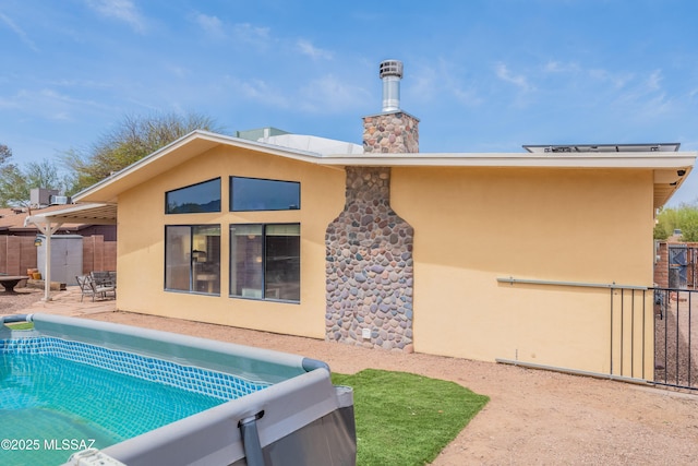 rear view of property with a patio area, fence, a fenced in pool, and stucco siding