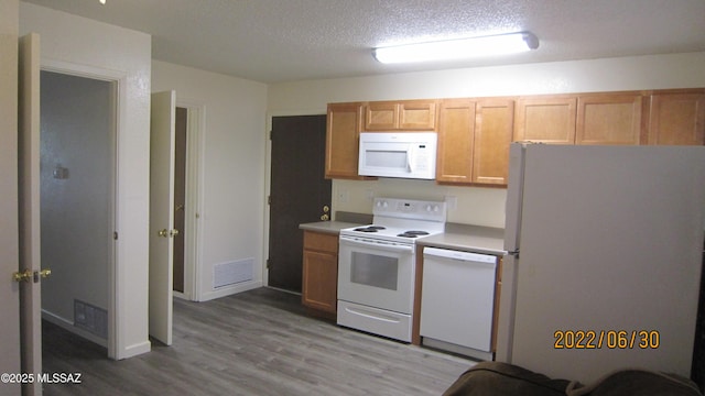 kitchen with white appliances, light countertops, visible vents, and a textured ceiling
