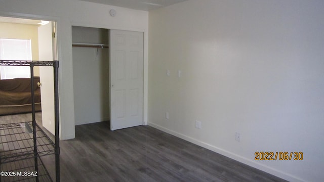 unfurnished bedroom with a closet, baseboards, and wood finished floors