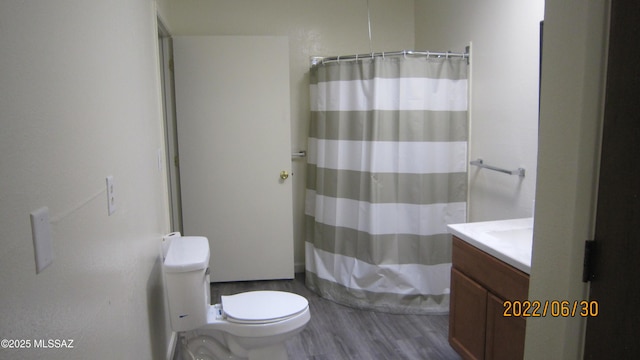 bathroom with vanity, a shower with shower curtain, toilet, and wood finished floors