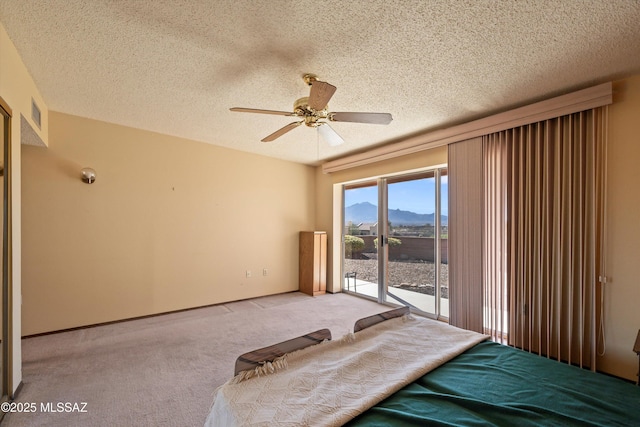 unfurnished bedroom featuring access to exterior, light carpet, a mountain view, and a textured ceiling