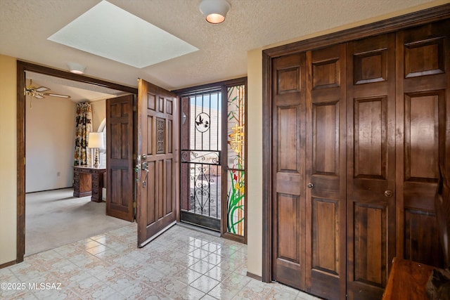 entryway featuring light carpet, a skylight, and a textured ceiling