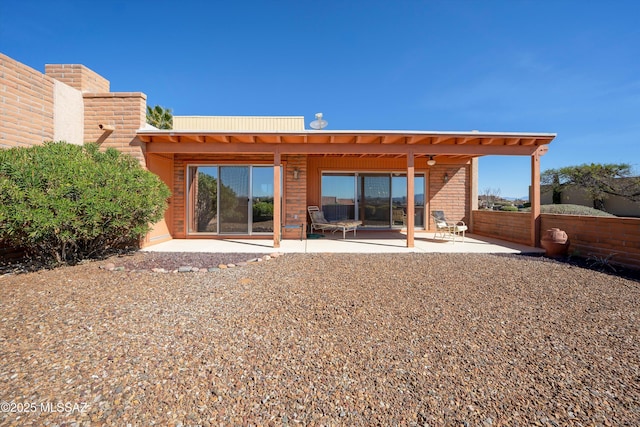 rear view of house with fence, brick siding, and a patio area