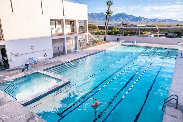 community pool featuring a patio area, a mountain view, a community hot tub, and stairs