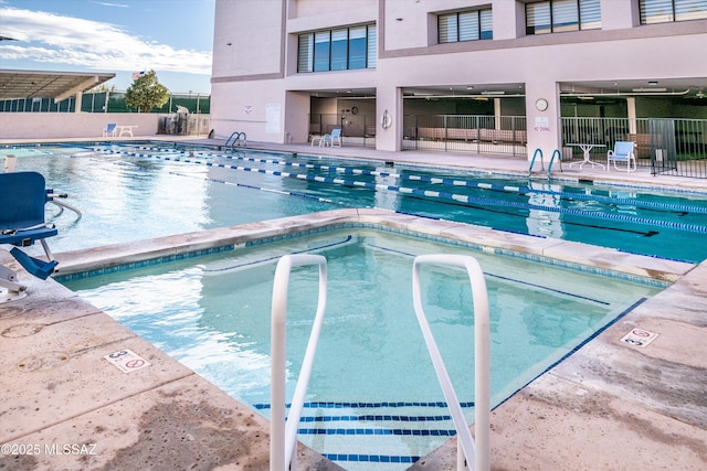 community pool with a patio area and fence