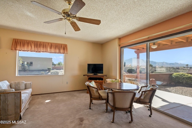 carpeted dining area with baseboards, a textured ceiling, and a ceiling fan