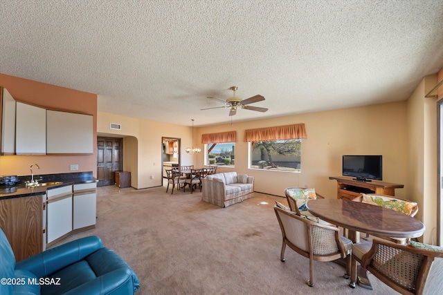 interior space with a textured ceiling, a ceiling fan, visible vents, and light carpet