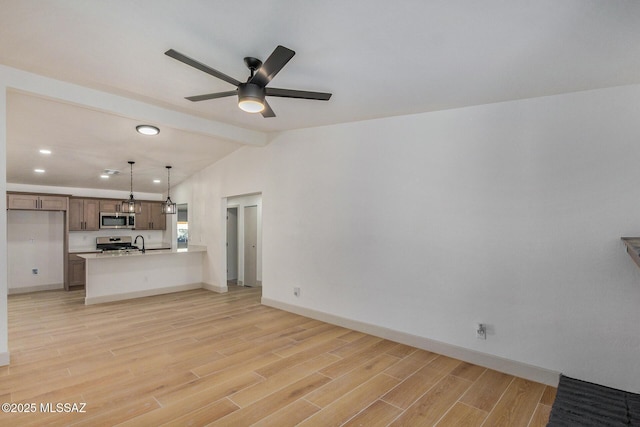 unfurnished living room with baseboards, vaulted ceiling with beams, a sink, ceiling fan, and light wood-type flooring