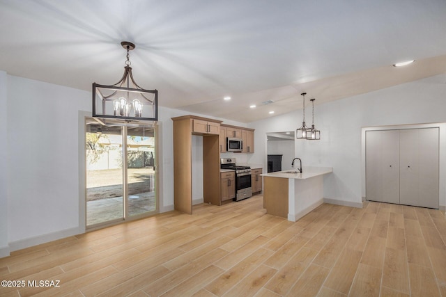 kitchen with lofted ceiling, appliances with stainless steel finishes, a peninsula, and an inviting chandelier