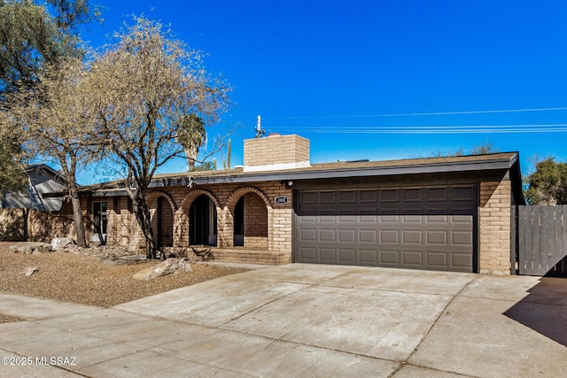 ranch-style house featuring brick siding, an attached garage, concrete driveway, and a chimney