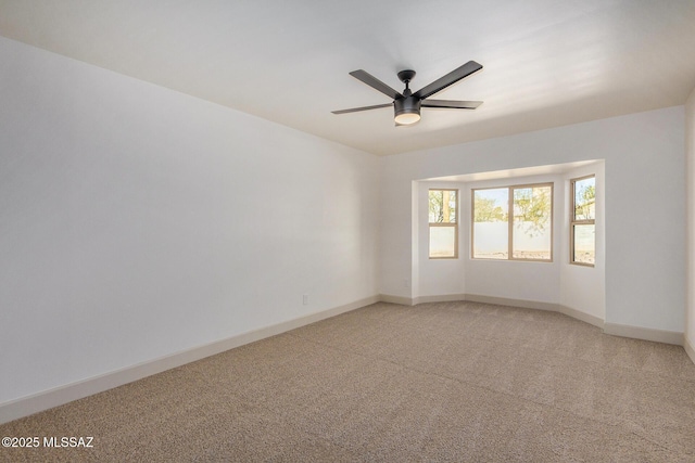 unfurnished room with light colored carpet, a ceiling fan, and baseboards