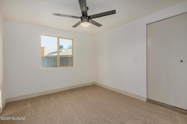 unfurnished bedroom with a closet, light colored carpet, baseboards, and ceiling fan