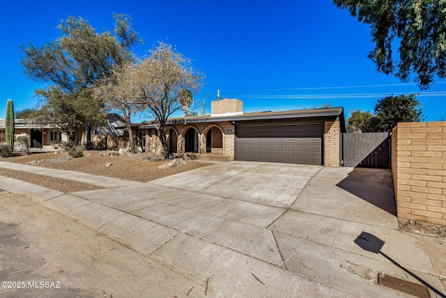 single story home with fence, driveway, a chimney, a garage, and brick siding