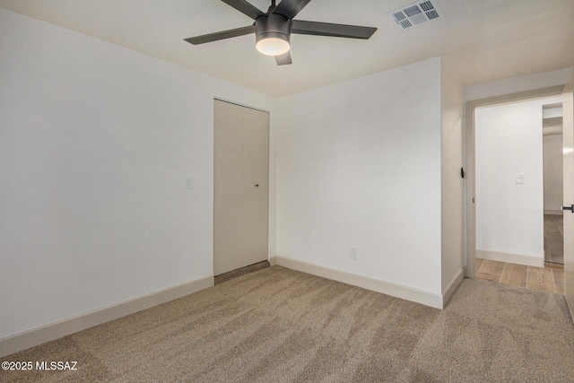 spare room featuring visible vents, baseboards, light carpet, and ceiling fan