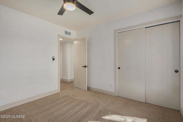 unfurnished bedroom featuring visible vents, ceiling fan, baseboards, light carpet, and a closet
