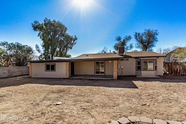 rear view of house with a patio, a chimney, central AC, and fence