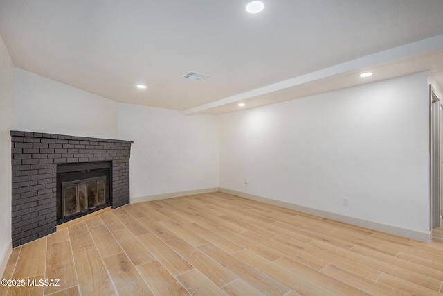 unfurnished living room with wood finished floors, visible vents, baseboards, a fireplace, and recessed lighting