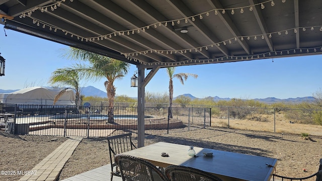 view of patio with a fenced backyard, a community pool, and a mountain view