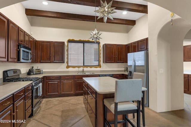 kitchen featuring a center island, stainless steel appliances, a breakfast bar, arched walkways, and beamed ceiling