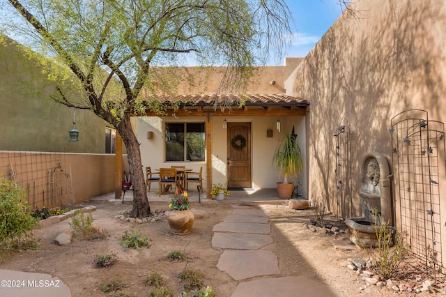 view of front of property featuring stucco siding, a tile roof, and a patio area