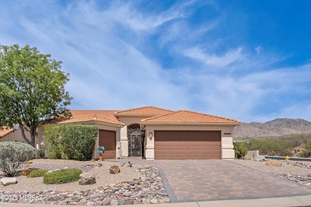 36973 S Highland Ridge Ct, Tucson, AZ 85739 - mediterranean / spanish home featuring an attached garage, a tile roof, stucco siding, and a mountain view