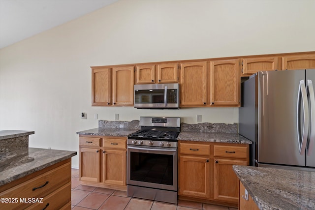 36973 S Highland Ridge Ct, Tucson, AZ 85739 - kitchen featuring stainless steel appliances, light tile patterned floors, dark stone counters, high vaulted ceiling, and brown cabinets