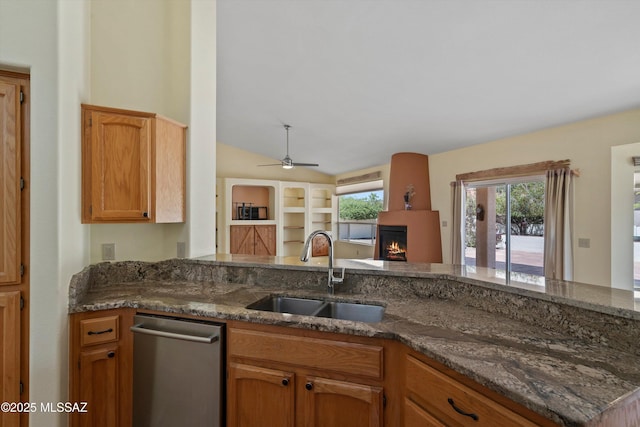 36973 S Highland Ridge Ct, Tucson, AZ 85739 - kitchen featuring a sink, a warm lit fireplace, dark stone counters, vaulted ceiling, and dishwasher