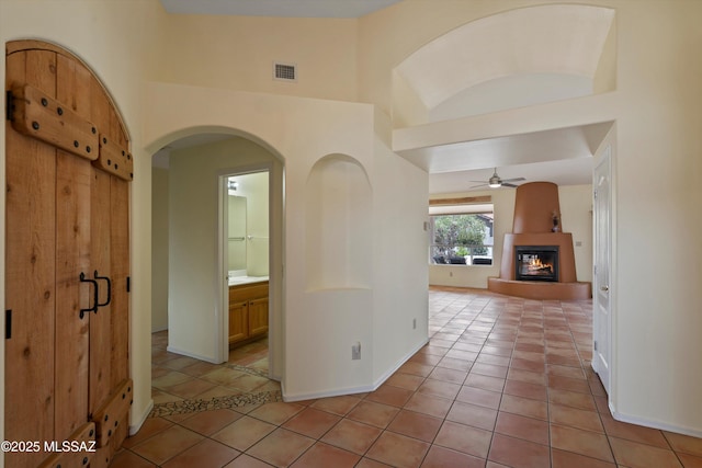 36973 S Highland Ridge Ct, Tucson, AZ 85739 - hallway featuring light tile patterned flooring, baseboards, a towering ceiling, and arched walkways