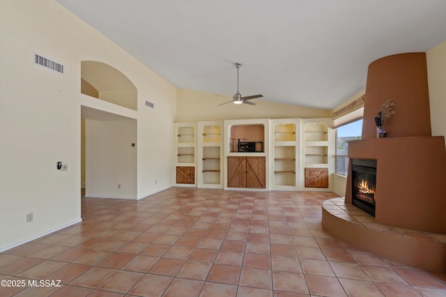 36973 S Highland Ridge Ct, Tucson, AZ 85739 - unfurnished living room with lofted ceiling, light tile patterned floors, a glass covered fireplace, a ceiling fan, and built in features