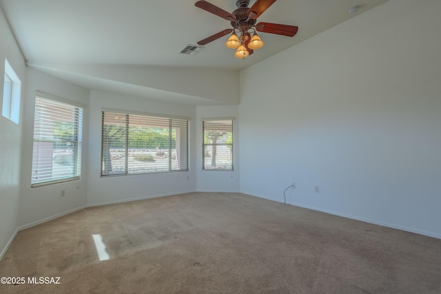 spare room with a wealth of natural light, visible vents, lofted ceiling, and carpet