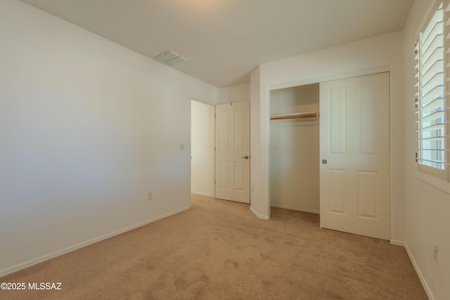 unfurnished bedroom featuring carpet floors, a closet, baseboards, and visible vents