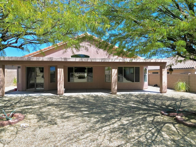 back of property featuring a patio, a tile roof, fence, and stucco siding