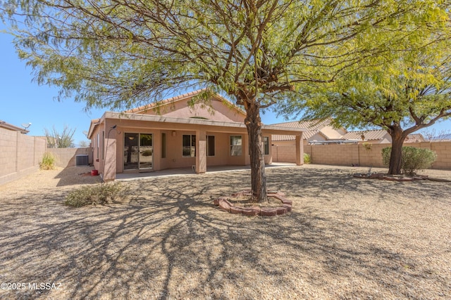 back of property with central AC unit, a tiled roof, a fenced backyard, stucco siding, and a patio area