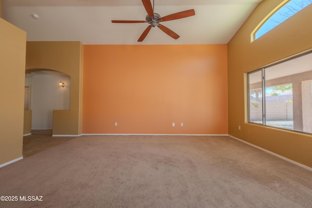 carpeted empty room with baseboards, arched walkways, and ceiling fan