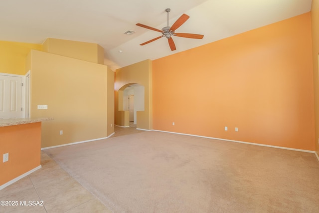 empty room featuring visible vents, arched walkways, light carpet, and ceiling fan