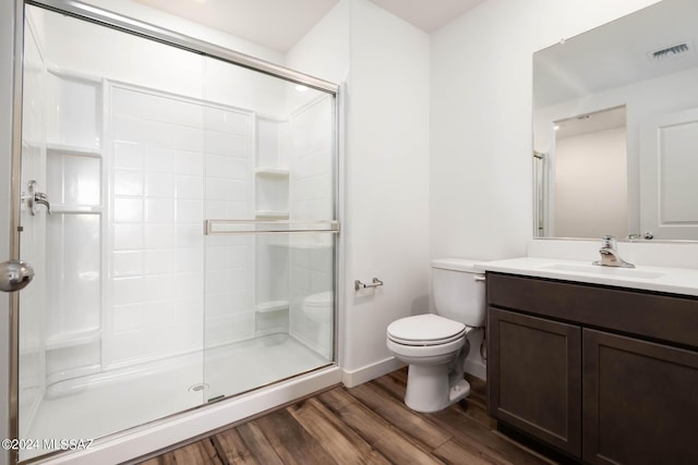 bathroom featuring visible vents, toilet, a stall shower, and wood finished floors