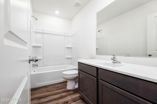 full bathroom with toilet, vanity, wood finished floors, washtub / shower combination, and visible vents