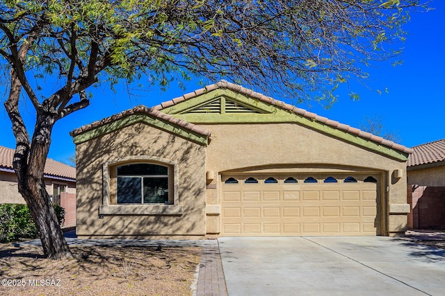 view of front of house featuring a tiled roof, a garage, driveway, and stucco siding