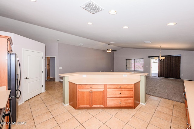 kitchen with visible vents, open floor plan, lofted ceiling, light tile patterned floors, and freestanding refrigerator