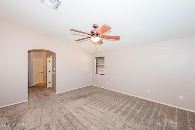 spare room with baseboards, visible vents, carpet floors, arched walkways, and ceiling fan