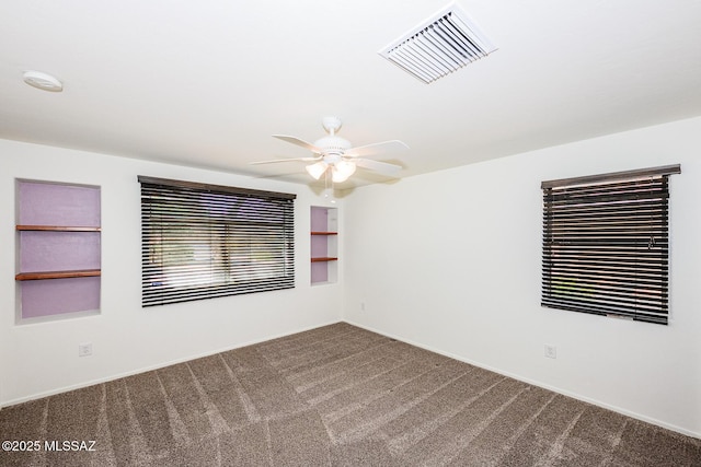 carpeted spare room with visible vents and a ceiling fan